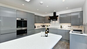 Een moderne keuken met een centraal eiland, inbouwapparatuur en een dakraam.