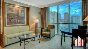 A hotel room with a large window, a sofa, a chair, a table, and a painting on the wall. - MGM Signature-Strip View Tower 2  Jacuzzi Studio (Las Vegas)