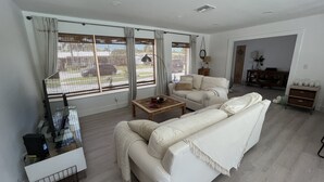 Ett modernt vardagsrum med en vit soffa, ett träbord och en tv som står på ett tv-bord.