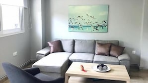 A modern living room with a sectional sofa, a coffee table, and a rocking chair. - Charming Apartment in Faliro (Palaio Faliro)