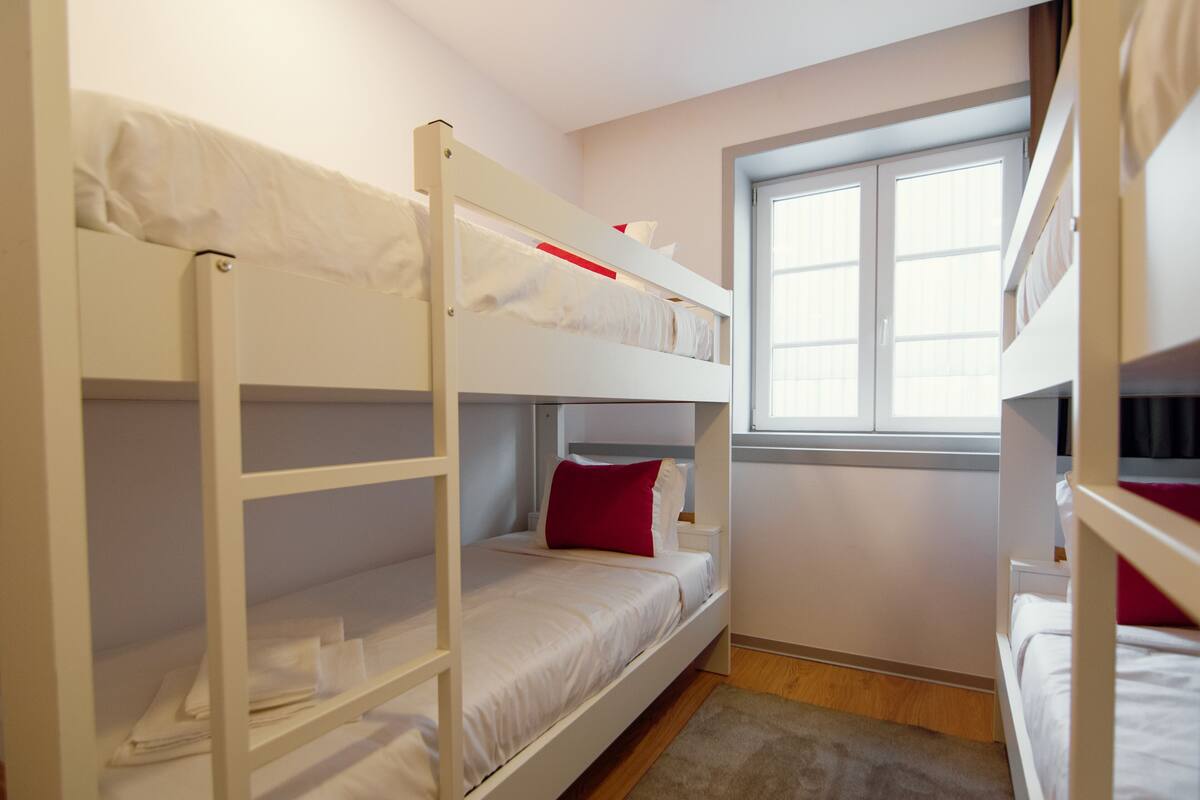 Une chambre avec un lit superposé, une fenêtre et une porte.