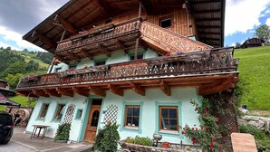 A traditional wooden chalet with a balcony, a wooden staircase, and a green door. - Vacation apartment on the farm (Wald)