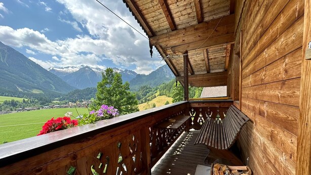 A wooden balcony with a view of mountains and a green valley. - Vacation apartment on the farm (Wald)