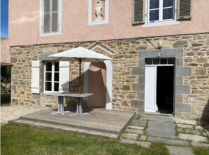 Traditional stone building with a wooden deck and grassy lawn.