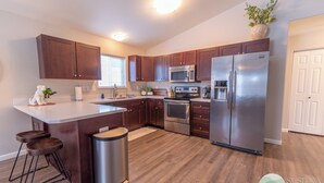 A modern kitchen with wooden cabinets, stainless steel appliances, and a central island. - Susitna Suites (Wasilla)