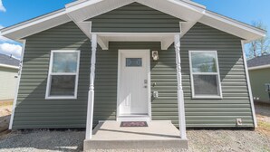 A single-story house with a front porch, a front door, and two windows on either side. - Susitna Suites (Wasilla)