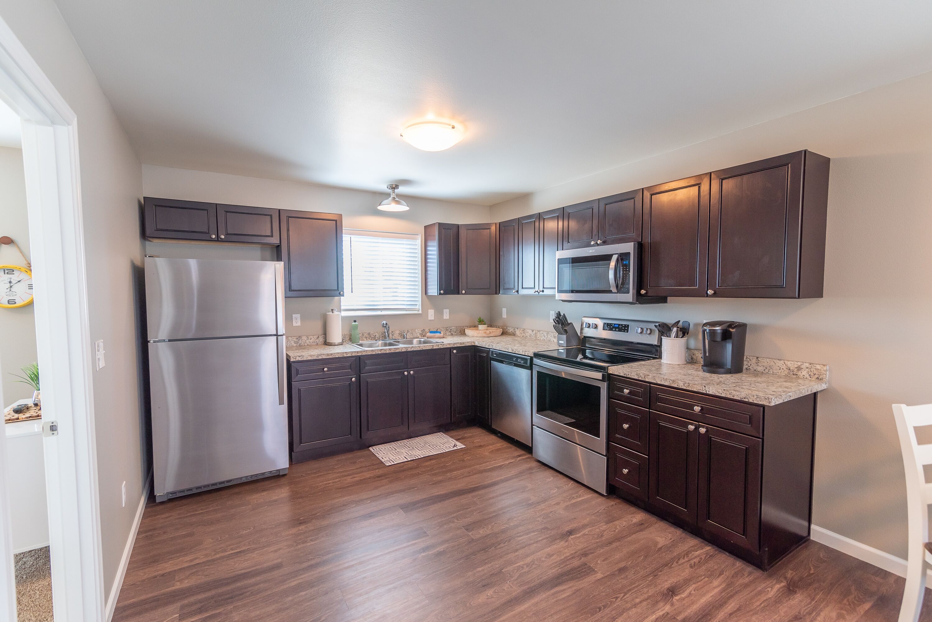 A modern kitchen with dark wood cabinets, stainless steel appliances, and a granite countertop.
