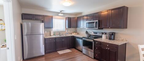 A modern kitchen with dark wood cabinets, stainless steel appliances, and a granite countertop.