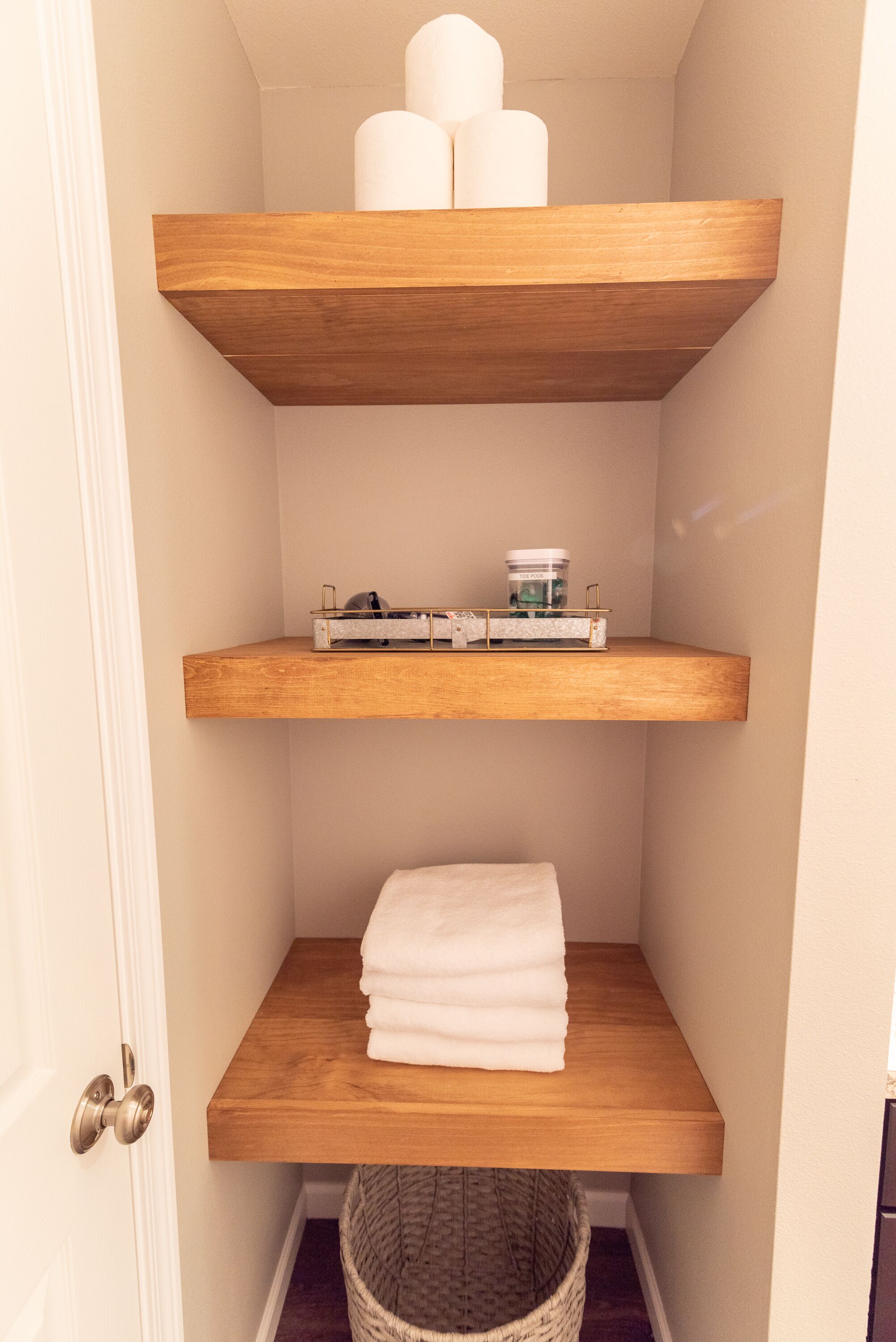 Eine Ecke mit drei Holzböden, auf denen verschiedene Gegenstände stehen.