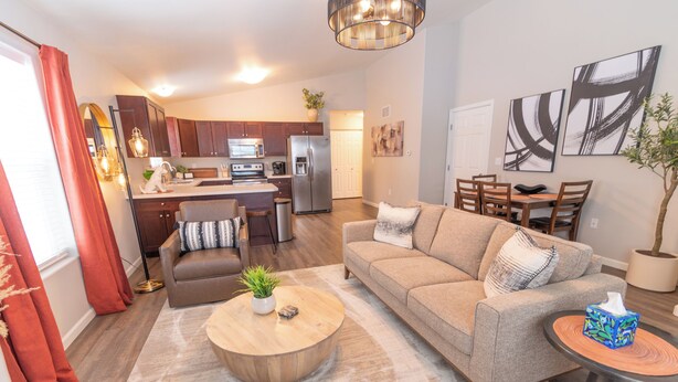 A modern living room with a sofa, coffee table, and dining area. - Susitna Suites (Wasilla)