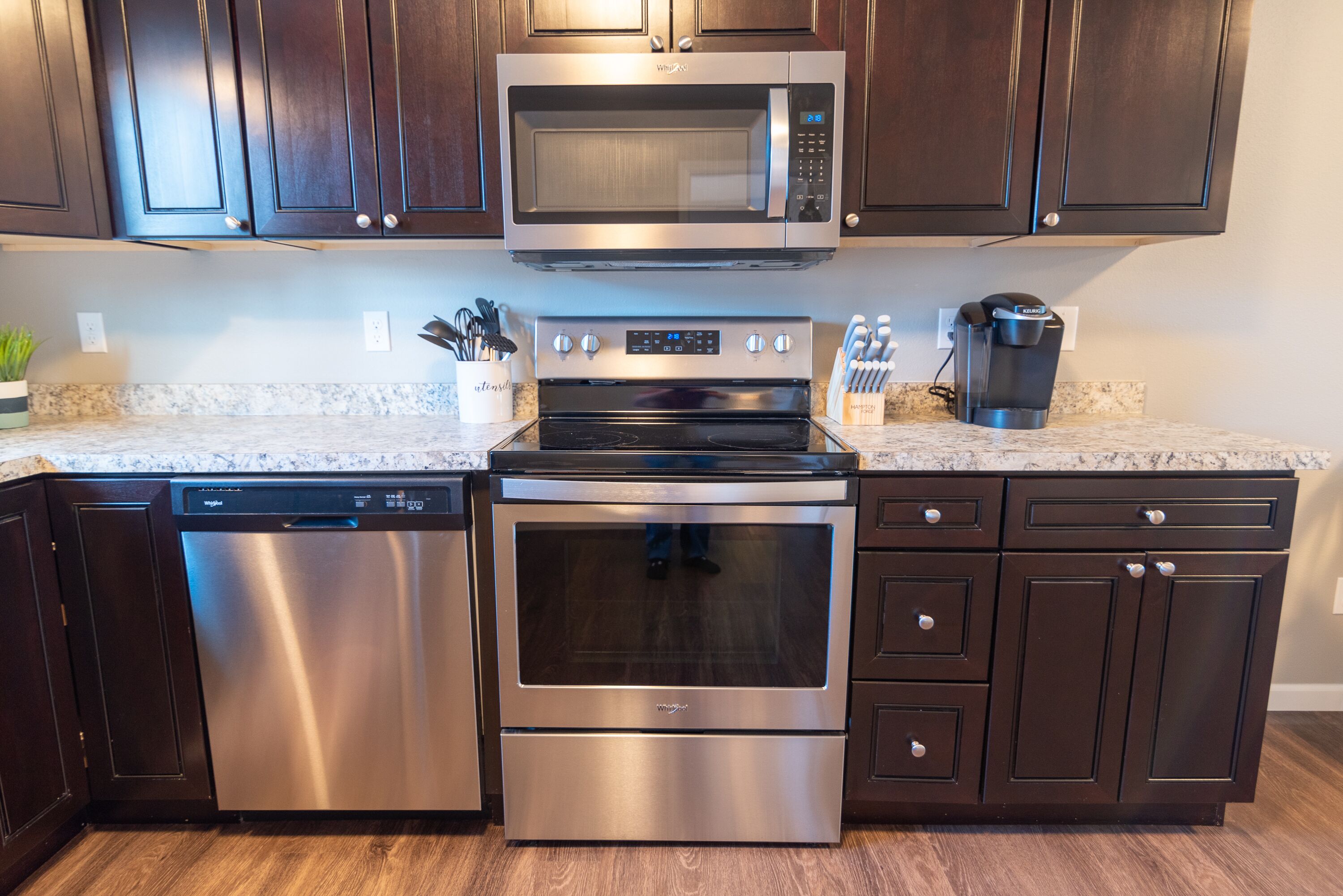 A kitchen with a stainless steel dishwasher, oven, microwave, and coffee maker.