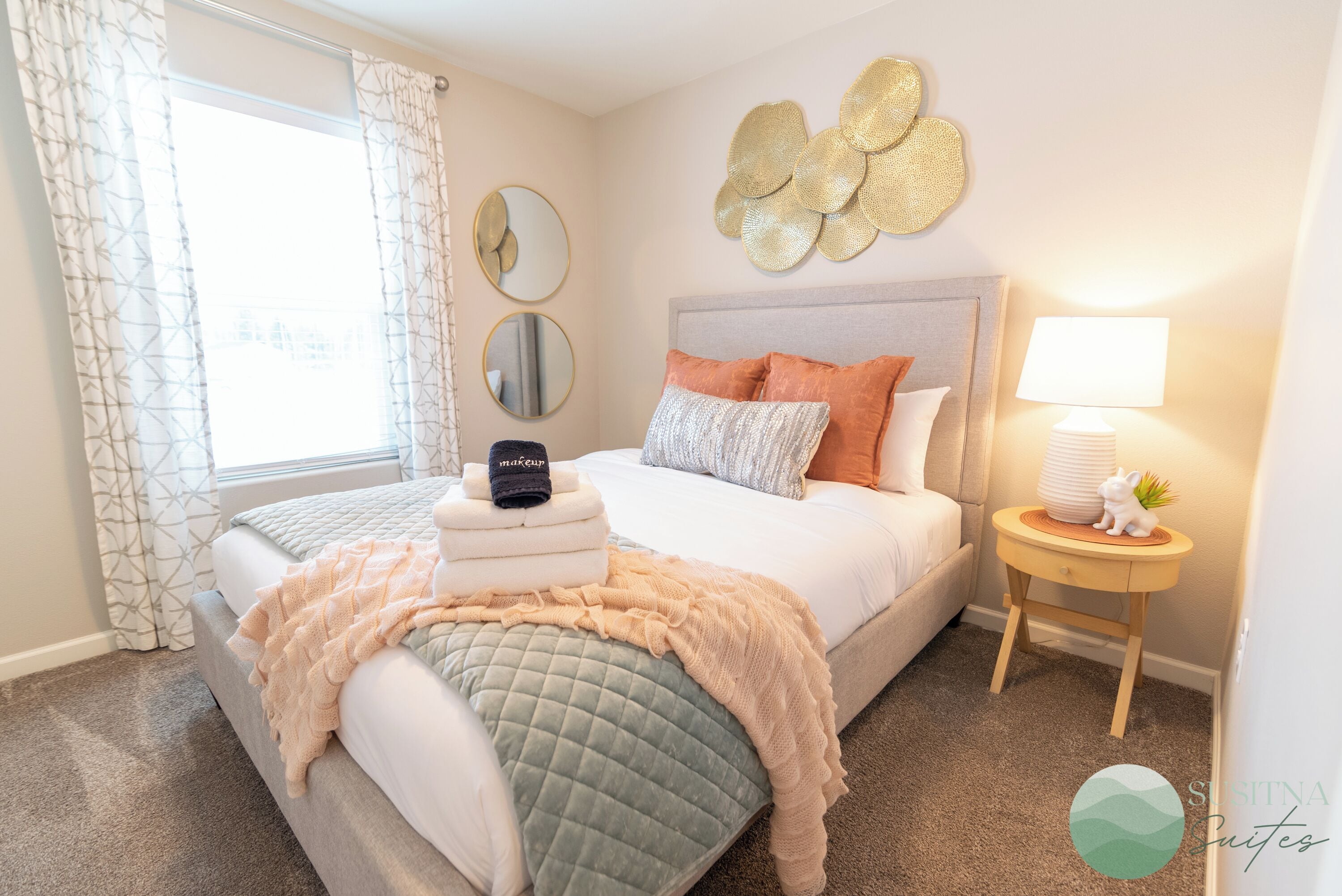 A neatly arranged bedroom with a bed, bedside table, and a window with curtains.