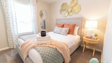 A neatly arranged bedroom with a bed, bedside table, and a window with curtains.