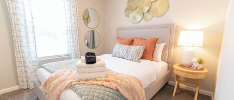 A neatly arranged bedroom with a bed, bedside table, and a window with curtains.