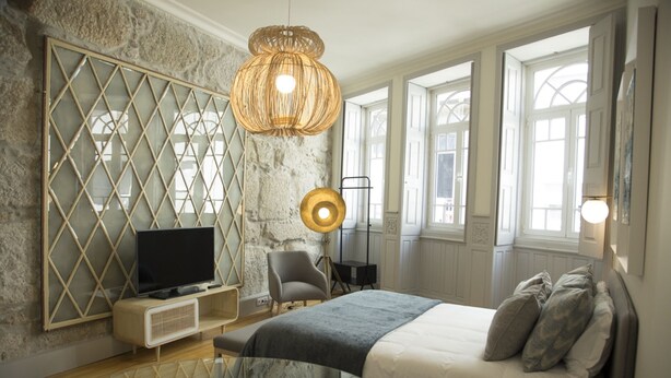 A modern bedroom with a large bed, a television, a glass table, and a unique wall design. - Top Porto (Porto)