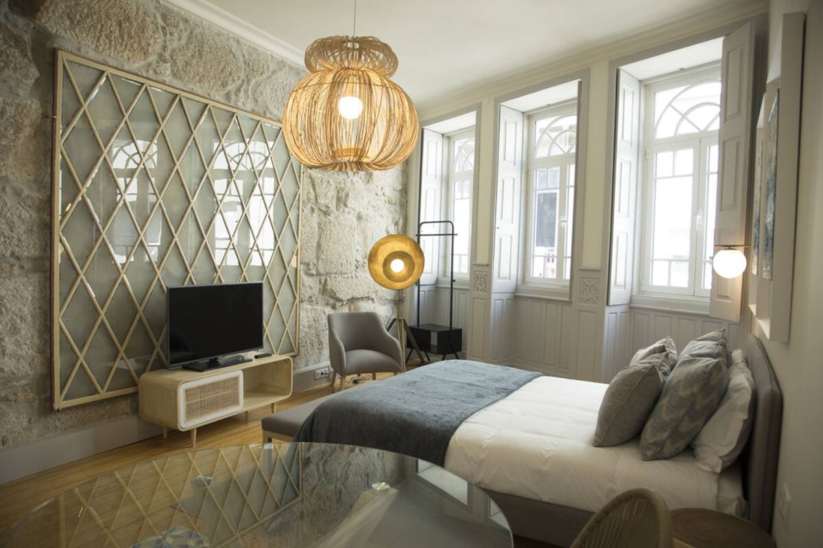 A modern bedroom with a large bed, a television, a glass table, and a unique wall design.