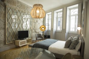 A modern bedroom with a large bed, a television, a glass table, and a unique wall design. - Top Porto (Porto)