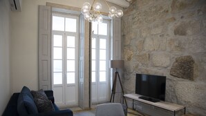A living room with a stone wall, a television, a sofa, and a lamp. - Top Porto (Porto)