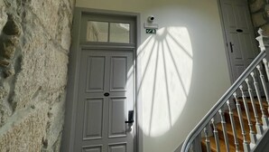 A staircase with a wooden handrail and a white door with a number plate. - Top Porto (Porto)