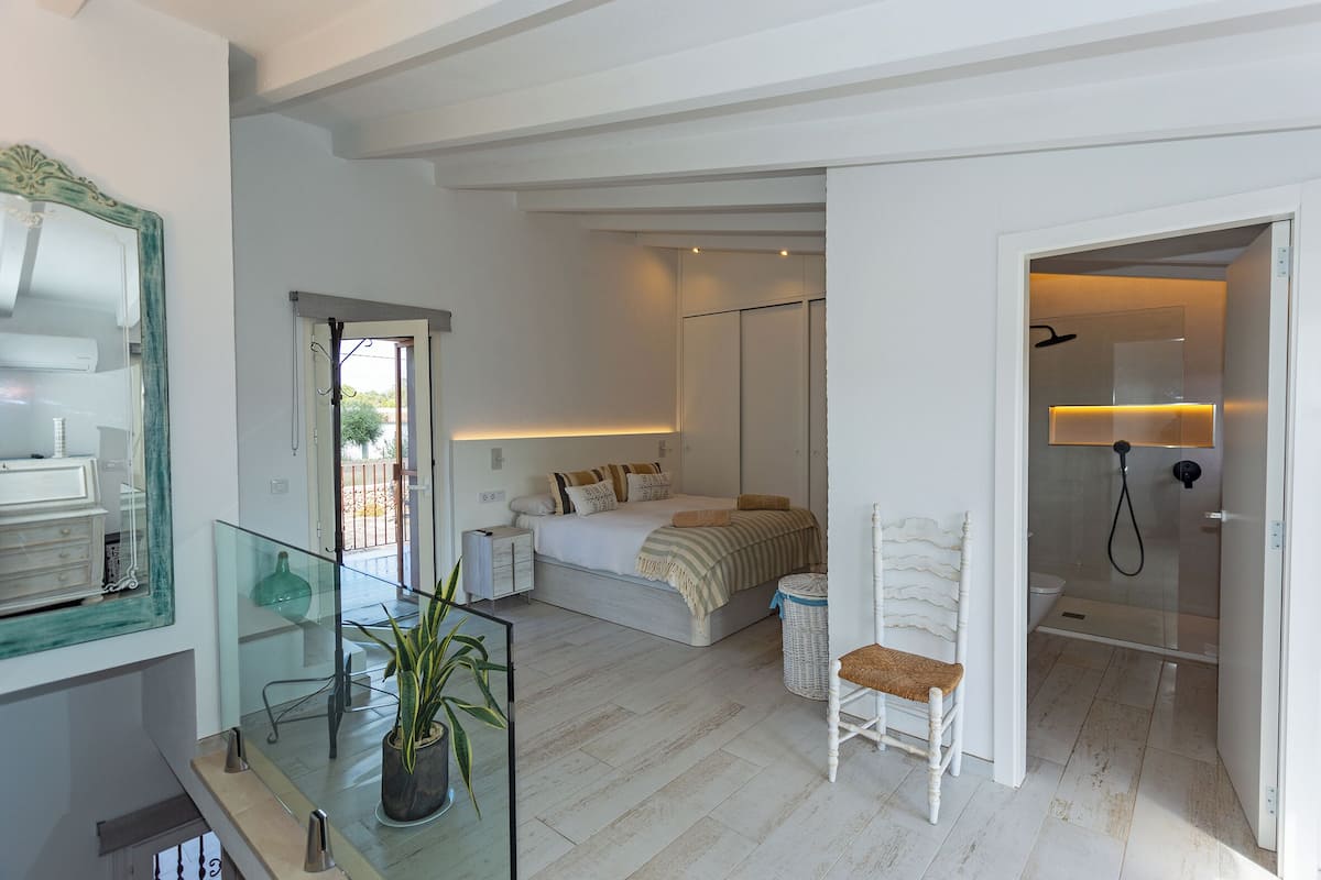 Une chambre à coucher comprenant un lit, une table de chevet et une chaise. Il y a aussi une salle de bain avec une douche et des toilettes.