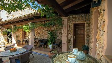 A patio area with wicker furniture, a glass table with wine corks, and a stone wall.