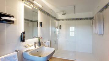 Un baño con lavabo, espejo, toallero y ducha.