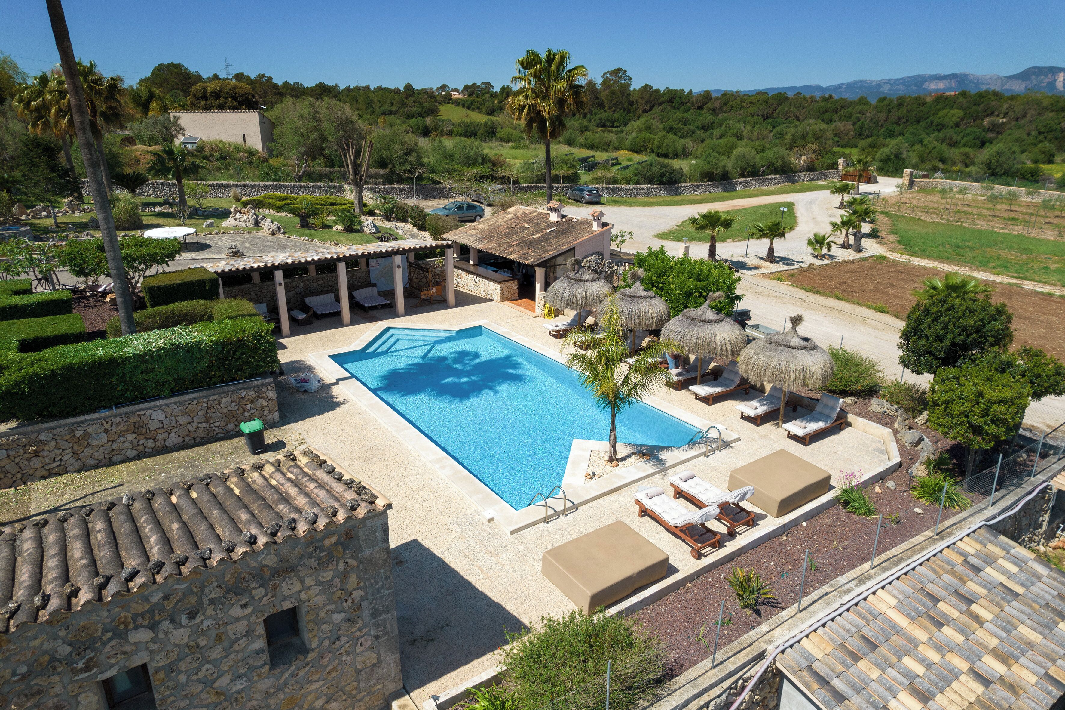 Une piscine avec des chaises longues, un bâtiment en pierre et une vue sur le paysage environnant.