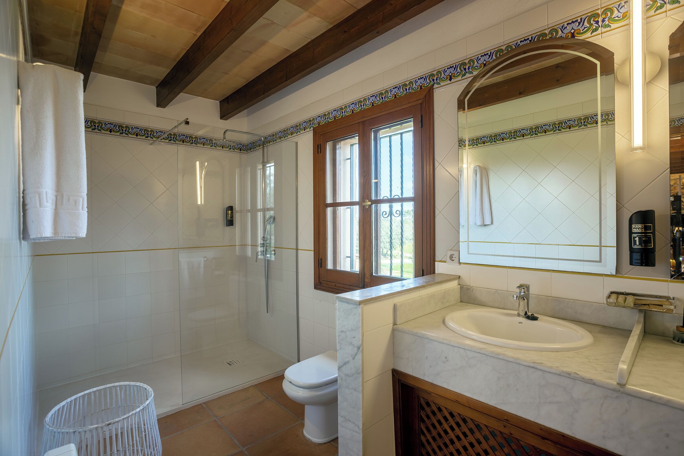 Un baño con ducha, inodoro, lavabo y ventana.