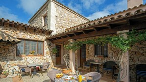 Un bâtiment en pierre doté d’un patio aménagé avec du mobilier d’extérieur, une table et des plantes en pot.