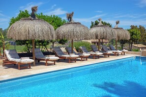 A swimming pool with lounge chairs and thatched umbrellas. - Agroturismo Ses Illes (Costitx)