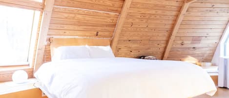 Ein Schlafzimmer aus Holz mit einem Bett, einem Fenster und einem Nachttisch.