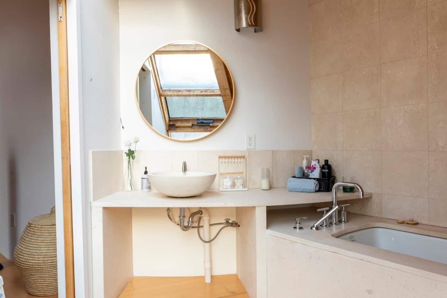 A modern bathroom with a round mirror, a white sink, and a bathtub.