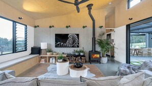 Ein modernes Wohnzimmer mit Kamin, großen Fenstern und Blick ins Freie.