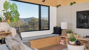 Ein modernes Wohnzimmer mit großem Fenster, einer eingebauten Bank und Blick ins Freie.