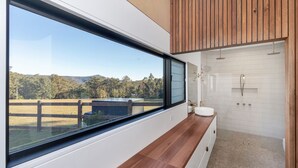 Ein modernes Badezimmer mit einem großen Fenster, einer Holzauslage und einer Duschkabine.