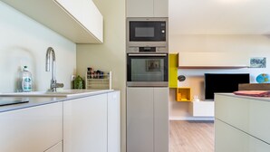 Cozinha moderna com armários brancos, forno de aço inoxidável e micro-ondas.