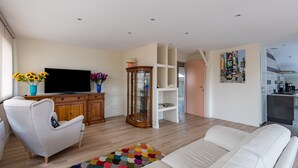 Un salon moderne avec un canapé, un téléviseur, un meuble en bois et un tapis coloré.