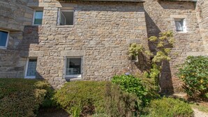 A stone building with multiple windows and a garden area with various shrubs. - La Naïade - à 200m de la plage (Carnac)