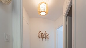 A hallway with wooden flooring, a wall-mounted decorative leaf art, and a ceiling light fixture. - La Naïade - à 200m de la plage (Carnac)