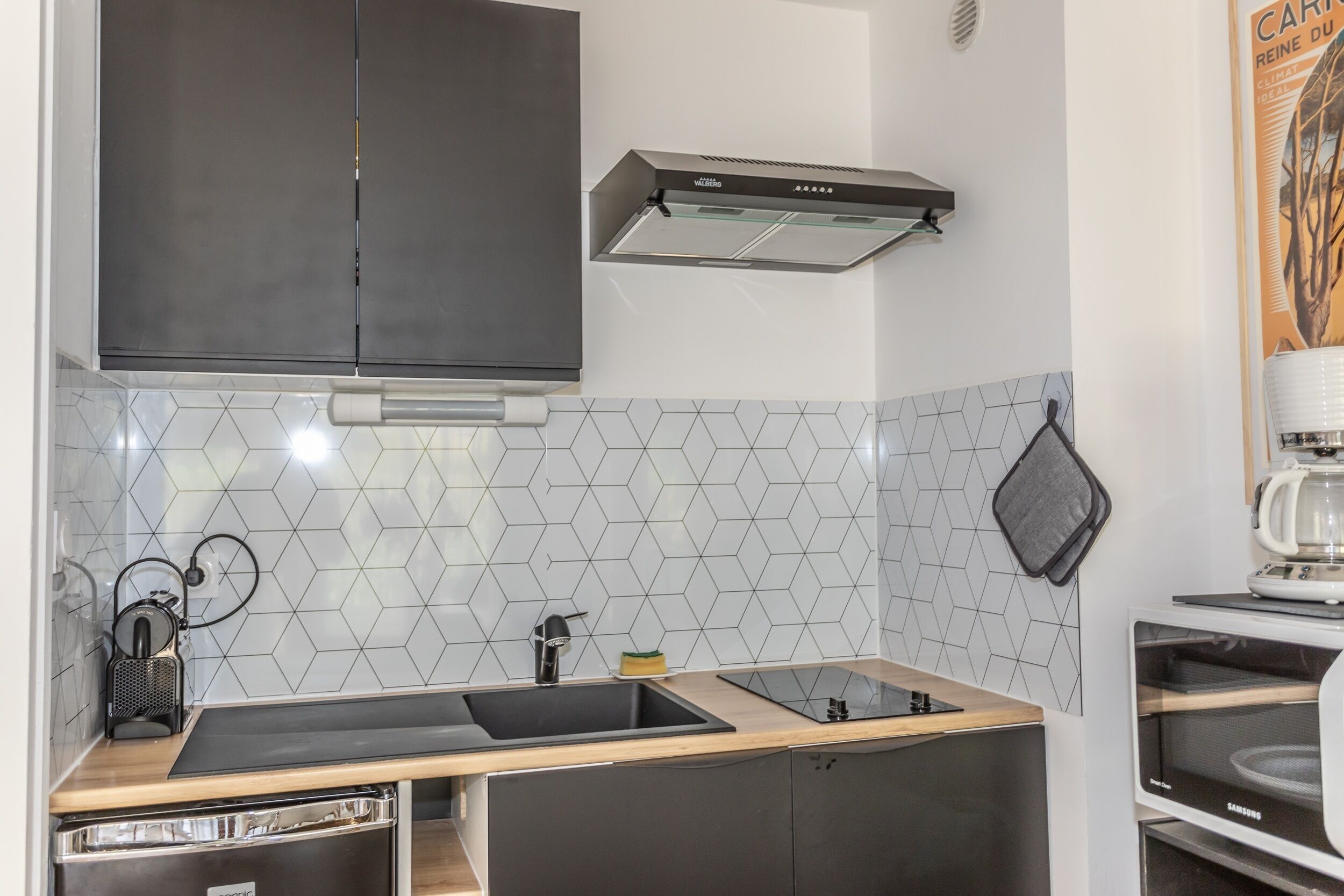 A compact kitchen with a double sink, a built-in oven, and a microwave.