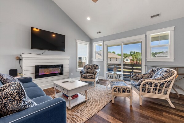 Relax in this stylish living room with a flat-screen TV, comfortable sofa, and wicker armchairs.