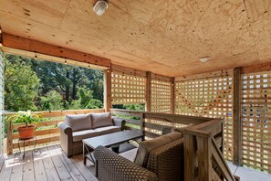 Relax in this serene outdoor seating area with a sofa, table, and chairs, surrounded by lush greenery.