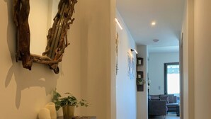 A hallway with a wooden console table, a mirror, and a potted plant. - Pythagorion Harbour Residence (Pythagoreio)