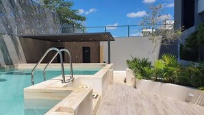 Zona de piscina en la azotea con vistas despejadas al cielo, un muelle de madera y un edificio pequeño al fondo.