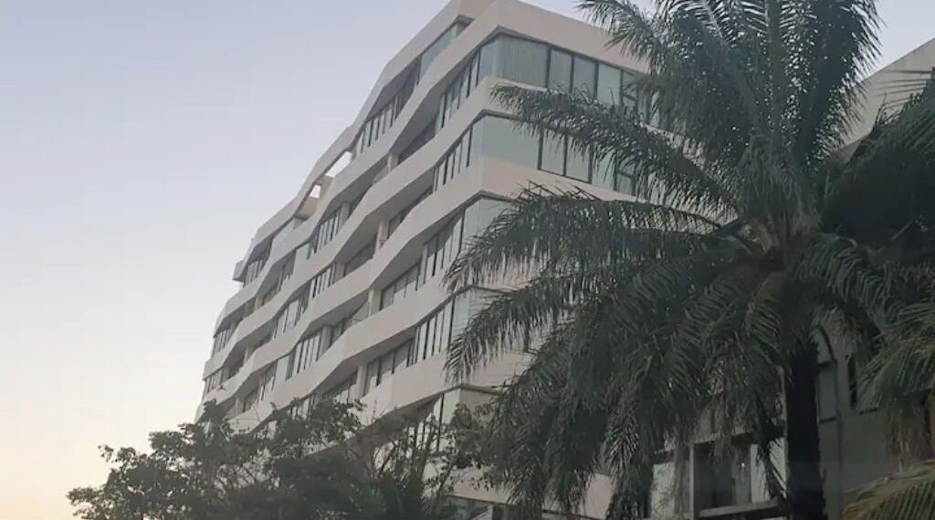 A multi-story building with a modern architectural design, featuring balconies and large windows.
