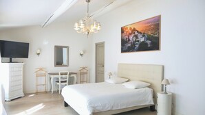 Un dormitorio con cama, mesita de noche, lámpara y un cuadro en la pared.