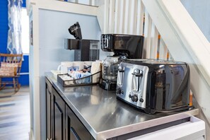A kitchenette with a toaster, coffee maker, and a coffee grinder on a stainless steel countertop. - Marcaritaville at La · Marcaritaville at Lake Barkley (Kuttawa)