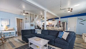 Een woonkamer met een donkerblauwe bank, een witte salontafel en een gestreept tapijt.