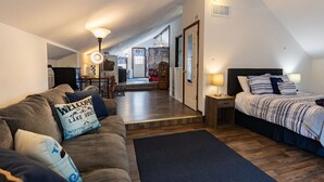 Een gezellige kamer met een bed, een bank, een lamp en een welkomstbord.
