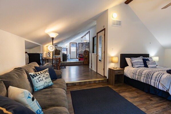 Une pièce confortable avec un lit, un canapé, une lampe et un panneau d’accueil.